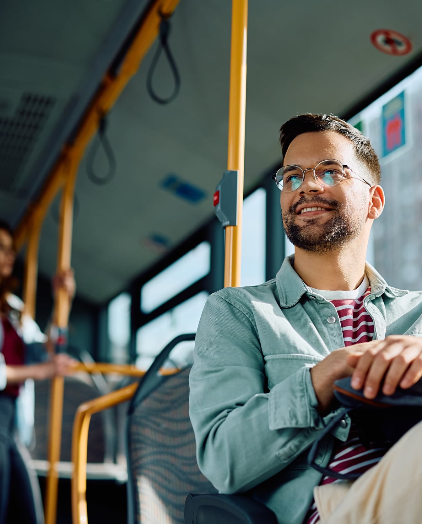 Man zit tevreden in de bus met tas op schoot. Reiziger is gefotografeerd vanaf onder.